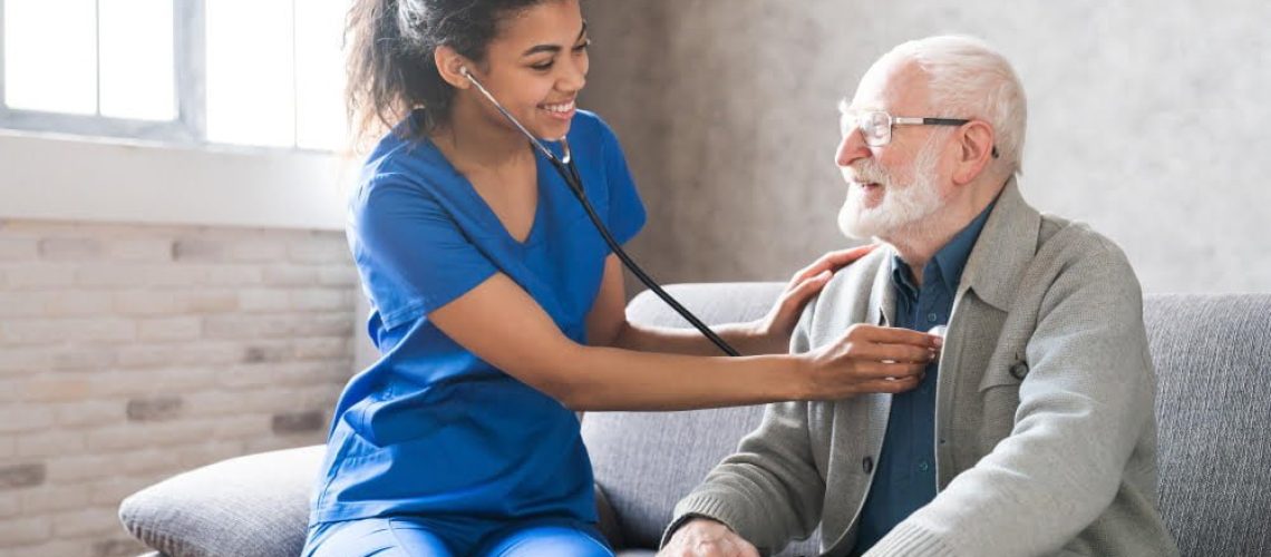 female-attending-physician-holding-stethoscope-listening-old-patient-during-homecare-visit
