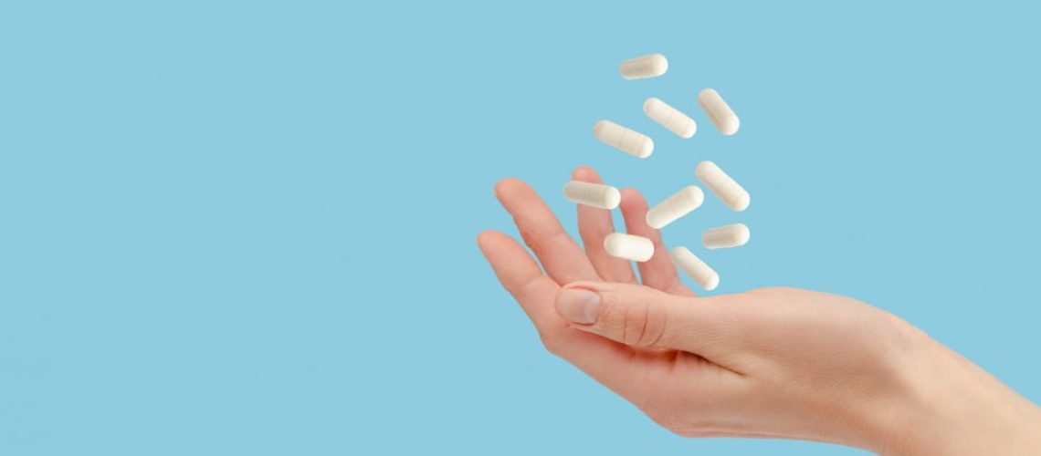 white-pills-floating-female-hand-isolated-blue-healthcare-treatment-concept-copy-space